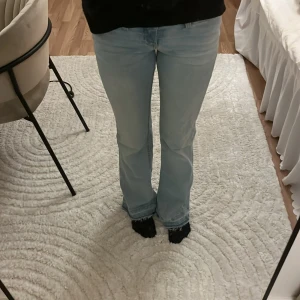 Bootcut jeans från Nelly, ljusblå - Snygga ljusblå bootcut jeans från Nelly med fransad midja och klassisk femficksdesign. Jeansen har en lätt tvättad look och är tillverkade i mjukt denimtyg som sitter skönt. Perfekt för dig som gillar retrovibbar och vill ha en cool siluett.