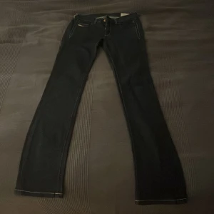 Diesel mörkblå bootcut jeans - Snygga mörkblå jeans från Disiel med bootcut passform och kontrasterande vita sömmar. Endast testade men har en pytteliten defekt som man ser på sista bilden. Annars är de i toppskick! Storleken är W25 men är försmå för mig som brukar ha W25/26. De är också lite långa för mig som är 168 cm. Ordinarie pris är mellan 1400-2500 och de är som sagt endast testade!