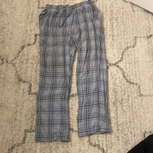 Blårutiga linnebyxor med snörning - Säljer ett par chill blårutiga linnebyxor med snörning i midjan. De har en avslappnad passform och är perfekta för varma dagar. Materialet är lätt och luftigt, och mönstret är klassiskt rutigt i olika blå nyanser.