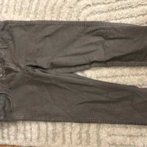 Grå raka low waist jeans med normal passform - Snygga grå low waist jeans med klassisk femficksdesign och raka ben. Jeansen har normal passform och är tillverkade i mjukt bomullsmaterial med en lätt tvättad look. Perfekt för dig som gillar stilrena och enkla jeans i en neutral färg.