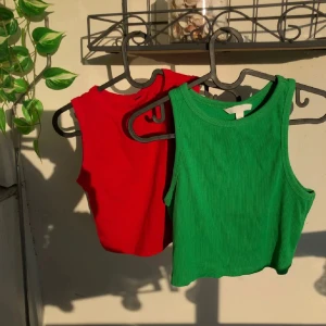 Grön och röd croppad linnetopp - Två croppade linnetoppar, en i klarrött och en i grönt. Den gröna är ribad matrial, båda är stretchiga o bekväma. 