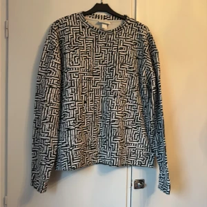 Svartvit  mönstrad från Monki st L - Cool långärmad tröja från Monki i storlek L med svartvitt grafiskt randigt mönster. Tröjan har rund halsringning och är gjord i mjuk bomull, perfekt för dig som gillar statement-plagg med unik look.