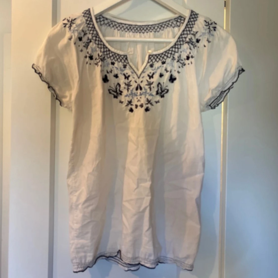 vit blus med blått broderi - 1