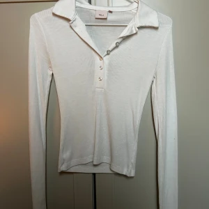 Vit ribbad polotopp från Nelly XS - Säljer en vit ribbad polotopp från Nelly i storlek XS. Toppen har lång ärm, klassisk krage och knappar framtill. Materialet är mjukt och stretchigt, perfekt för en clean och stilren look. Passformen är slim och toppen är något croppad. Använd ca 1-2 gånger 🌟🤍