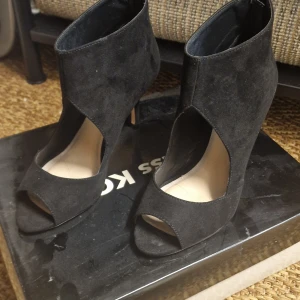 Miss KG - Svarta stövletter - Snygga svarta stövletter från Miss KG i svart suede med öppen tå och hög klack. Skorna är i ny skick. Har en modern cut-out design som ger en cool och edgy look. Perfekta för dig som vill sticka ut med stilrena detaljer och elegant siluett.