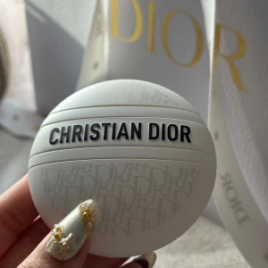 Dior Le Baume Multi-Use Balm 50ml - Lyxig vit balm från Dior i rund förpackning med silvergrå logomönster och svart text. Kan användas på läppar, händer och kropp. Snygg design som känns exklusiv och modern, perfekt att ha med i väskan. Innehåller 50 ml och är tillverkad i Frankrike.
