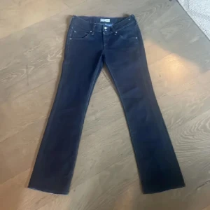 Mörkblå bootcut jeans från Lee - Snygga mörkblå jeans från Lee med klassisk femficksdesign och bootcut-ben. Jeansen har låg midja och är tillverkade i stretchig denim för en bekväm passform. Perfekta för dig som gillar en tidlös och stilren look. Midjemått ca 39 cm innerbenslängd ca 80 cm