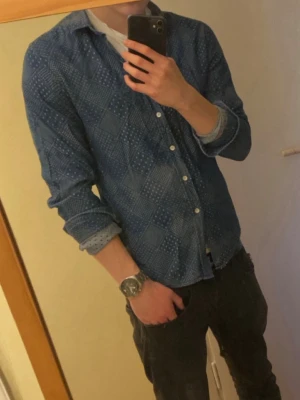 Blå mönstrad skjorta från Clubs & Spades - Snygg blå skjorta från Clubs & Spades med vitt geometriskt mönster och knappar framtill. Skjortan är tillverkad i bomull och har riktigt bra passform, och inga defekter alls 😁