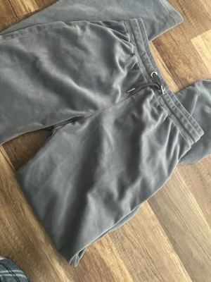 Grå mjukisbyxor - Säljer ett par grå mjukisbyxor med resår i midjan. Byxorna har raka ben och är gjorda i ett mjukt, lent material som känns riktigt skönt mot huden. Perfekta för chill dagar hemma eller när du vill vara bekväm.