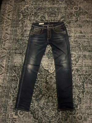 Mörkblå slim fit jeans från Repley - Snygga mörkblå slim fit jeans från Repley med slitningar och kontrastsömmar. Modell: slim fit George. Klassisk femficksmodell med läderpatch bak i midjan. Perfekta för en trendig och avslappnad look.