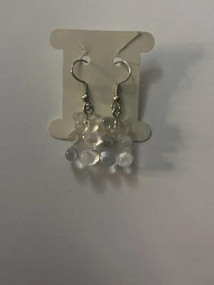 Genomskinliga pärlörhängen - Säljer ett par handgjorda örhängen med små, genomskinliga pärlor i kluster. Örhängena har silvriga krokar och en modern, lekfull design som passar dig som gillar unika accessoarer.