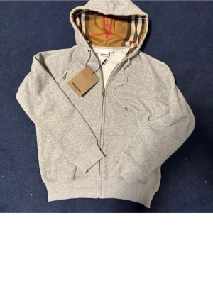Grå burberry hoodie  - Helt ny skick. Storlek XL i barnstorlek och sitter ungefär som S. Skulle säga att 170cm är rimlig längd