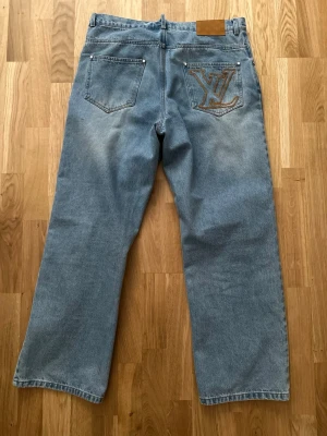 Louis Vuitton jeans  - Säljer ett par unika blå Louis Vuitton jeans med fantastiska detaljer. Byxorna är i nytt skick och har bara använts några gånger då den är för kort för mig. Storlek 31 Byxorna har en avslappnad, rak passform (Straight/Loose fit) som sitter riktigt snyggt