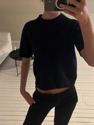 Stickad tshirt - En mörkblå stickad topp med korta ärmar och rund hals. Mjuk och bekväm kvalitet.