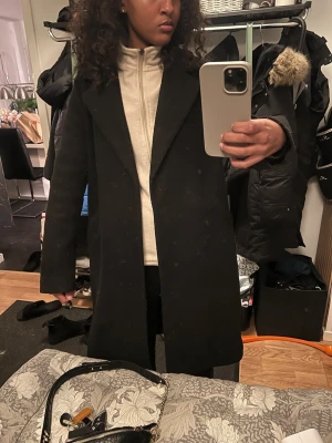 Svart lång kappa med bälte - Säljer en svart lång kappa med och bälte i midjan, kappan slutar vid knäna 