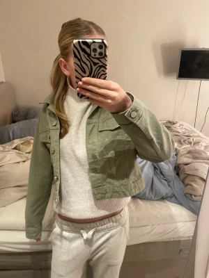Ljusgrön croppad jeansjacka - Snygg ljusgrön croppad jeansjacka med klassisk krage och knappar framtill. Jackan har två bröstfickor med lock och långa ärmar. Perfekt för dig som vill ha en chill och trendig look. Den är från gina tricot men köpte den här ifårn! men jag har aldrig använt den! Storleken är M men skulle mer säga xs-s💚