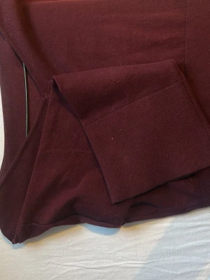 Mörkröd långärmad tröja - Säljer en mörkröd långärmad tröja i mjukt material. Tröjan har bred mudd vid ärmslut och midja, och en enkel, stilren design utan synliga detaljer. Perfekt för dig som gillar basic men ändå vill ha en snygg färg.