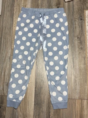Blå prickiga pyjamasbyxor H&M strl M - Mysiga blå pyjamasbyxor från H&M i storlek M med stora vita prickar och bred resår i midjan. Perfekta för chill dagar hemma.
