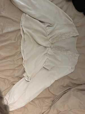 En vit blus med urringning  - Det är en urringad blus som är vit , väldigt fin men lite genomskinlig. 