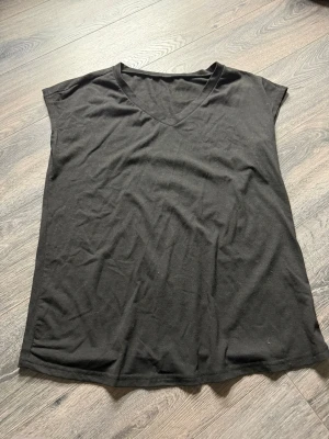 Svart v-ringad ärmlös topp - En enkel svart topp med v-ringning och ärmlös design. Tillverkad i mjukt bomullstyg som känns skönt mot huden. Perfekt att matcha med jeans eller kjol för en clean och avslappnad look.