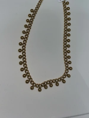 Guldfärgad kedja med bollar - Säljer ett snyggt halsband i guldplätering med små bollar längs hela kedjan. Längden är 37+5 cm och halsbandet har en klassisk karbinhake. Perfekt för att ge din outfit en trendig touch.