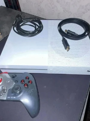 Xbox One S - Xbox One S i vitt med tillhörande strömkabel, HDMI-kabel och en specialdesignad handkontroll (RIG XT7 PRO). Konsolen och kontrollen visar visst slitage och repor, men allt ser komplett ut för spelstart.