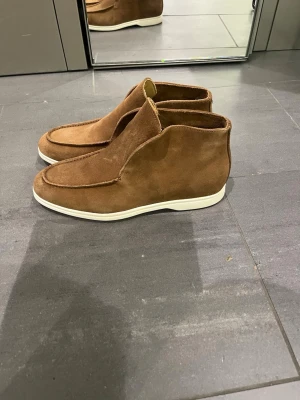 High loafers - Säljer ett par helt nya stilrena loafers i brun mocka med vit, platt sula i storlek 43. Endast provade, aldrig använda. Nypris 3 600 kr.