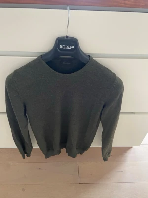 Mörkgrön stickad tröja Stenströms - Mörkgrön stickad tröja från Stenströms med rund halsringning och långa ärmar. Enkel och stilren design som passar perfekt till lager på lager under höst och vinter. Skön och mjuk kvalitet som känns lyxig. Storlek S