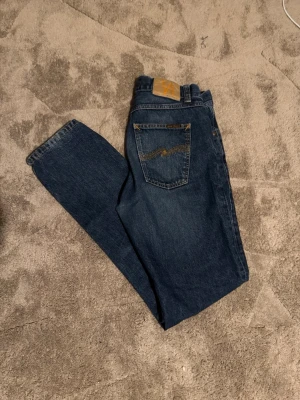 Blå jeans från Nudie Jeans  - Säljer ett par klassiska blå jeans från Nudie Jeans,  frånDe har fem fickor, gylf med dragkedja och knapp samt Nudie-logga på bakfickan. Perfekta för dig som gillar en enkel och tidlös stil.