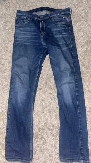 Blå Replay jeans straight fit - Säljer ett par klassiska blå jeans från Replay i modellen THAD. Jeansen har raka ben, fem fickor och snygga kontrastsömmar. Märkesdetaljer på fickan och bak. Tillverkade i slitstarkt denimtyg som ger en tidlös look.