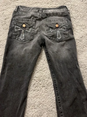 Grå jeans med broderade fickor Gina Tricot - Säljer ett par gråa flare jeans från Gina Tricot i storlek 158. Jeansen har snygga broderade detaljer på bakfickorna och kopparfärgade knappar. Klassisk femficksmodell med normal passform och cool tvättad look. Använt dom några gånger men dom är hela. 