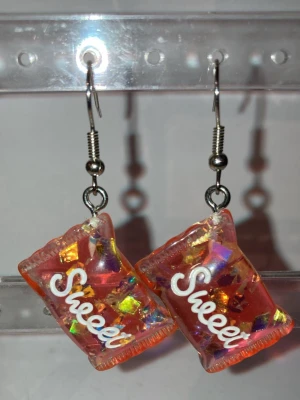 Örhängen  - Handgjorda örhängen som görs av mig. Med röda godis påsar på sig . Frakten är ca 22-100kr beroende på vikten på produkten . Kontakta mig om du vill köpa.