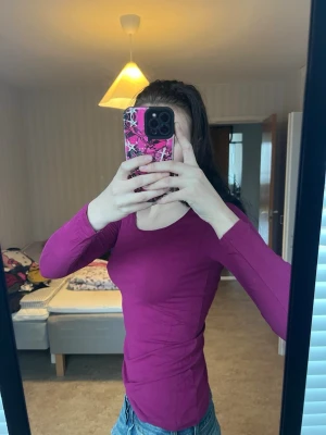 Mörkrosa långärmad topp - En enkel och snygg mörkrosa långärmad topp med rund halsringning. Modellen är figurnära och passar perfekt till jeans eller kjol. Materialet känns mjukt och stretchigt, vilket gör den bekväm att bära hela dagen.