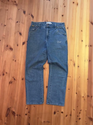 Blå jeans från Dime med broderi - Säljer ett par klassiska blå jeans från Dime med broderad logga både fram och bak. Jeansen har raka ben, normal passform och fem fickor. Tillverkade i slitstark denim med en snygg vintagekänsla. Perfekta för dig som gillar streetwear och enkel stil.