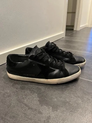 Golden goose skor svart - Säljer dessa tvärfeta o ganska sällsynta golden goose skor i svart färg med vita sulor. De passar perfekt nu inför våren, och även andra årstider. Skorna är storlek 45, använda men i bra skick. Förutom att hälen skrapats lite, dock syns det inte när man använder de. Nypris: 5000-6000kr. 