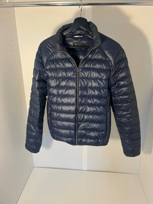 Mörkblå lätt dunjacka från Riley - Säljer en mörkblå dunjacka från Riley i storlek S. Hör av dig vid eventuella frågor