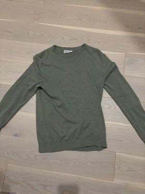 Grön tröja från Kappahl, storlek S - En enkel och stilren grön tröja från Kappahl i storlek S. Tröjan har rund halsringning och långa ärmar. Perfekt basplagg till garderoben och passar till många olika outfits. Liten defekt på ärmen vid handleden går o sy ihop inget man märker