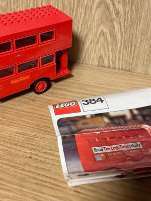 Röd LEGO Londonbuss 384 - Säljer en ikonisk röd Londonbuss från LEGO, modell 384. Dubbelvåningsbussen har detaljerade fönster, skyltar med 'Piccadilly' och 'Visit Lego Land', samt texten 'London Transport' på sidan. Perfekt för dig som gillar klassiska LEGO-modeller och brittisk stil.
