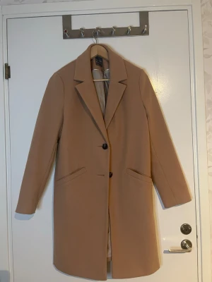Beige kappa från Primark, strl 40 - Beige kappa från Primark med två knappar och två fram fickor. 