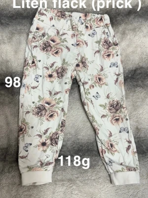 Blommiga mjukisbyxor  - Supersköna mjukisbyxor med blommigt mönster i pastellfärger och små fjärilar. Byxorna har resår i midjan och muddar vid bensluten för extra komfort. Perfekta för chill dagar hemma eller lek utomhus.🌸 Liten fläck ( prick ). Storlek 98