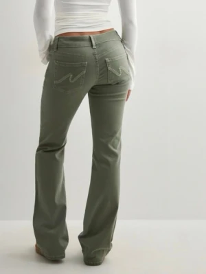 Gröna bootcut jeans med broderade fickor - Snygga gröna jeans med bootcut passform och broderade detaljer på bakfickorna. Byxorna har normal midja och är tillverkade i ett mjukt bomullsmaterial. Perfekta för dig som vill ha en avslappnad men trendig look. Ny pris 700kr