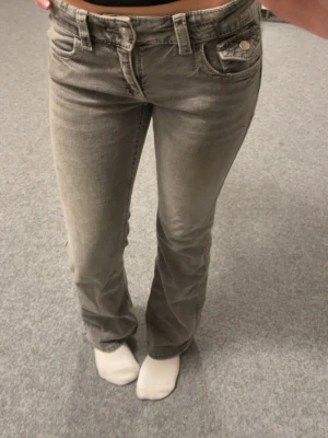 Grå lågmidjade bootcut jeans Gina Tricot - Ett par gråa lågmidjade bootcut jeans från Gina Tricot i storlek 164. Jeansen har snygga detaljer på bakfickorna. Även en liten ficka framtill. Använda fåtal gånger.