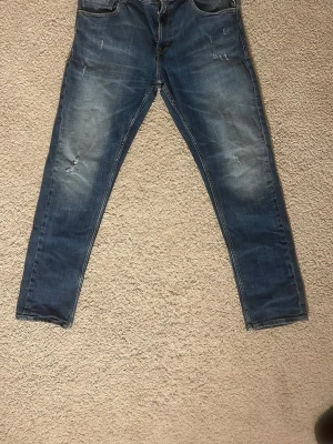 Replay blå jeans slim tapered 32/30 - Säljer ett par blå Replay jeans i modellen MickyM med slim tapered passform. Jeansen har snygga slitningar och ett hål som en del av designen. Pris kan diskuteras 