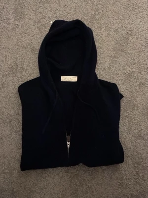  cashmere hoodie från Sayless - Mysig svart hoodie från Sayless i lyxig cashmere. Tröjan har huva med snörning och dragkedja framtill med snygg läderdetalj på zipparen. Perfekt för dig som vill ha något både chill och stilrent i garderoben. Tröjan är ny utan prislapp då jag inte kunde lämna tillbaka den efter att jag använt den hemma 