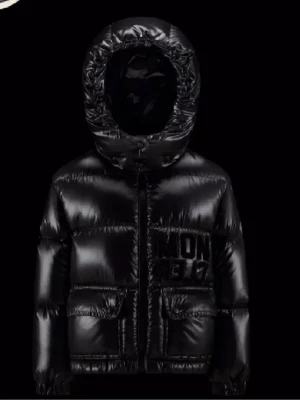 Svart Moncler pufferjacka med huva - Säljer en svart, glansig pufferjacka från Moncler med stor broderad logga på bröstet. Jackan har huva, dragkedja framtill och två stora fickor med lock och knapp. Perfekt för kalla dagar och riktigt snygg till vinterns outfits. Är 14y men passar xs-m jag har lappen den kom med samt tygpåsen den kom i. Köpt för 8400kr original pris 