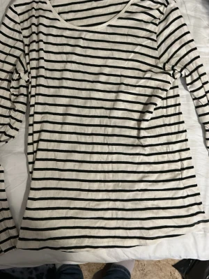 Randig långärmad topp från H&M - Säljer en vit och svart långärmad topp från H&M i storlek XL. Toppen har smala horisontella ränder och är tillverkad i ribbad bomull. Perfekt för en avslappnad och stilren look.
