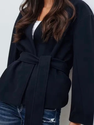 Blå omlottjacka med bälte - Snygg blå omlottjacka med bälte i midjan som ger en cool och modern siluett. Jackan har lång ärm och är tillverkad i ett mjukt material som känns skönt mot kroppen. Perfekt för dig som gillar minimalistisk stil och vill ha en jacka som sticker ut.