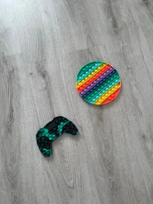 Fidget toy (pop it) - Bilden visar inga västar till salu, endast två pop it-leksaker i olika färger och former.