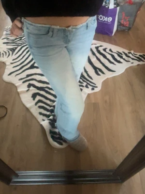 Ljusblå lågmidjade bootcut jeans  - Säljer ett par ljusblå jeans med bootcut passform och avklippa upp till vilket ger jeansen ett mer vintage utseende. Perfekta för dig som gillar en avslappnad och trendig look. ny skick, säljes pga kommer inte till användning.