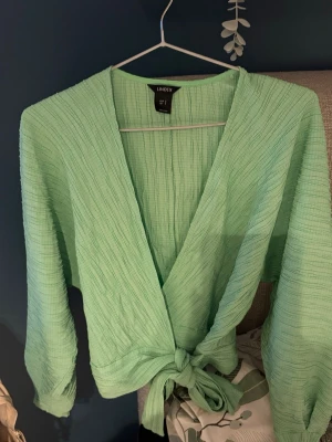 Grön omlottopp från Lindex - Säljer en ljusgrön omlottopp från Lindex med knyt framtill. Alltså en omlott blus. Färgen e mest lik på de sista bilderna! Som ny💕